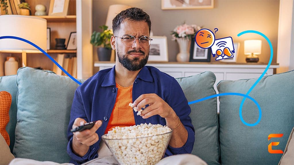 Man sitting on blue couch while eating popcorn and trying to find something to watch