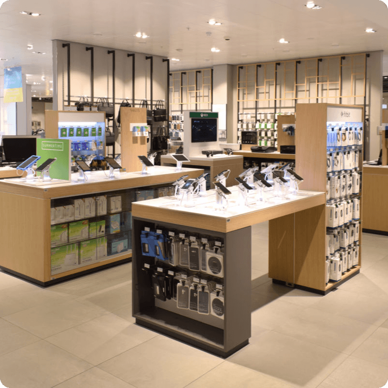 Interior view of a modern John Lewis & Partners store with shoppers, various product displays, and a "Click & Collect" counter.
