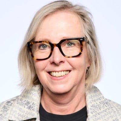 Headshot of a smiling woman with blonde hair and tortoise shell glasses.