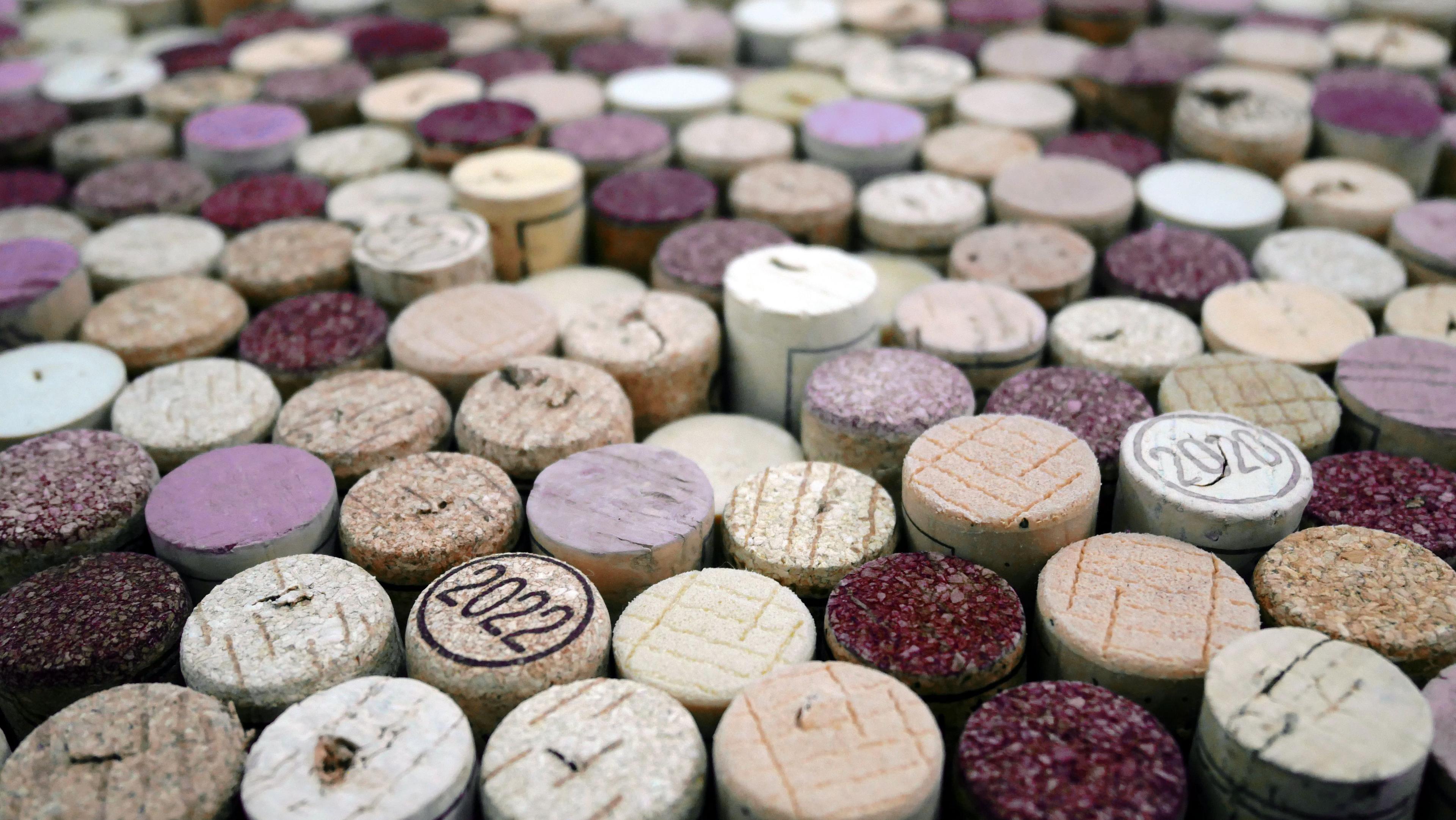Many wine corks, stained red and purple, with years like '2022' and '2020' visible on some.