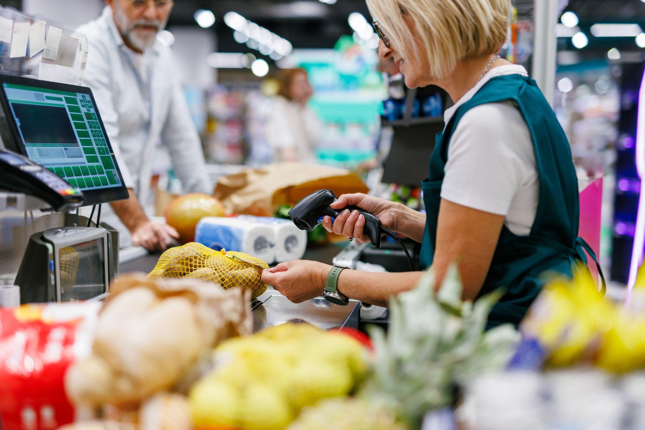 A cashier scanning groceries at a supermarket checkout.